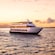 A multilevel ship sailing through open water at sunset